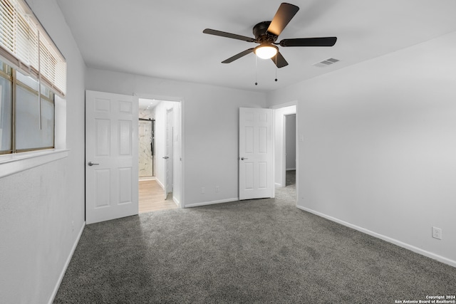 unfurnished bedroom with ceiling fan and dark carpet