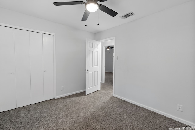 unfurnished bedroom featuring dark colored carpet, ceiling fan, and a closet