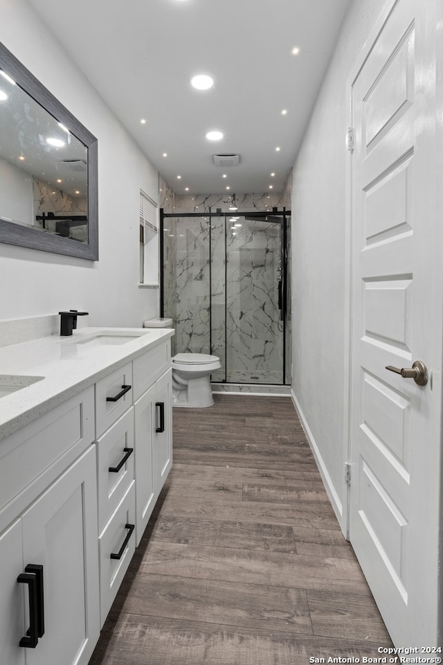 bathroom with a shower with door, dual bowl vanity, toilet, and hardwood / wood-style floors