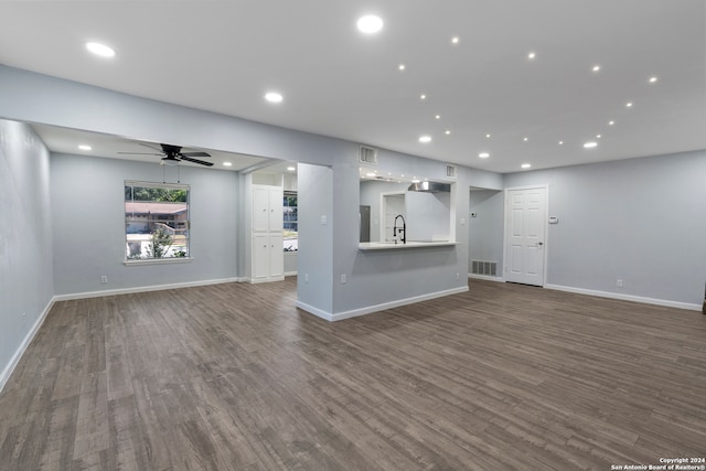 unfurnished living room with ceiling fan, sink, and dark wood-type flooring