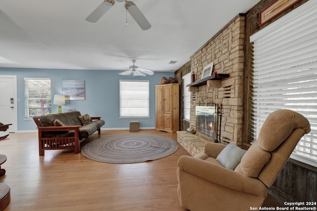 living room featuring a stone fireplace, hardwood / wood-style flooring, and ceiling fan