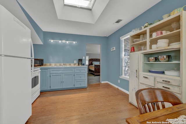 kitchen with white appliances, sink, light hardwood / wood-style floors, and a skylight