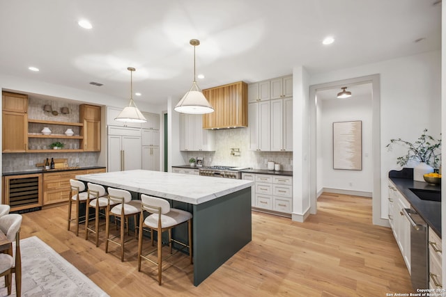 kitchen featuring beverage cooler, stainless steel dishwasher, tasteful backsplash, a breakfast bar area, and paneled built in fridge