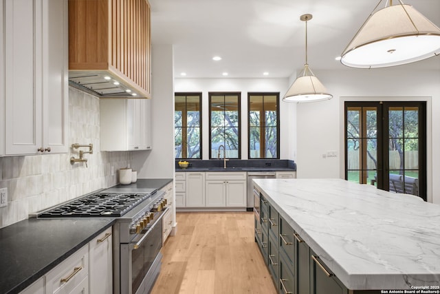 kitchen featuring appliances with stainless steel finishes, a sink, custom range hood, white cabinetry, and recessed lighting