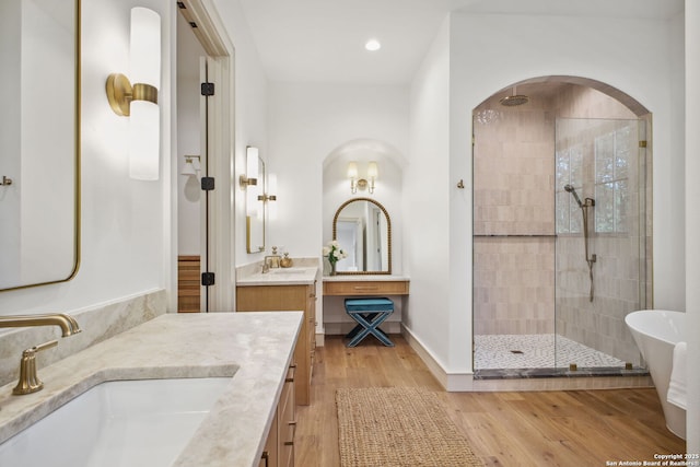 bathroom featuring a shower stall, wood finished floors, two vanities, and recessed lighting