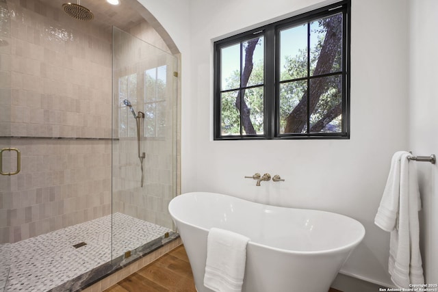 full bathroom with a stall shower, a soaking tub, and wood finished floors