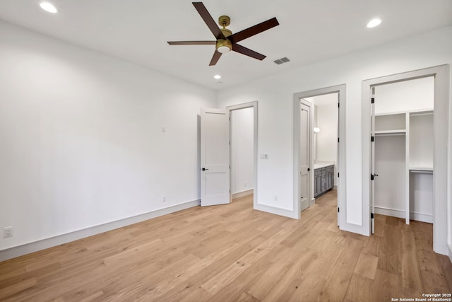 unfurnished bedroom with light wood-style floors, a spacious closet, recessed lighting, ensuite bath, and baseboards