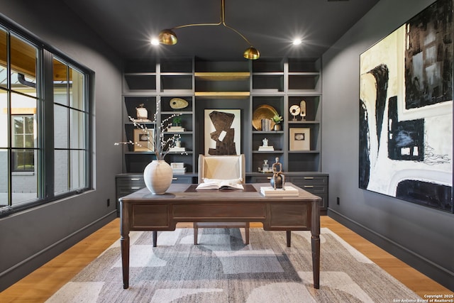 office area with wood finished floors, baseboards, and built in features
