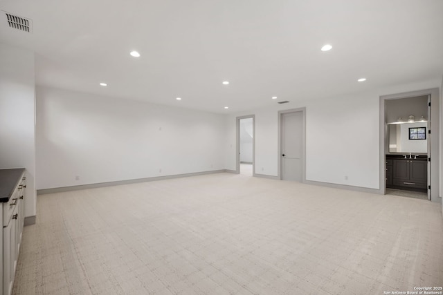 unfurnished living room with recessed lighting, baseboards, and light carpet