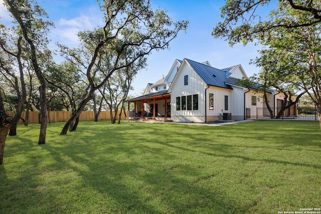 back of house with board and batten siding, metal roof, a standing seam roof, and a patio