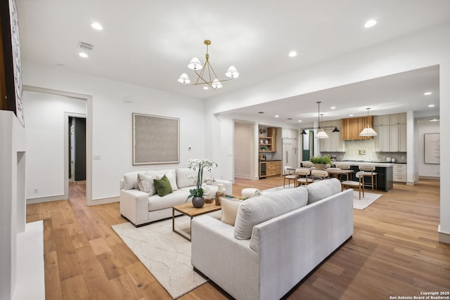 living area featuring recessed lighting, a chandelier, light wood-style floors, and baseboards