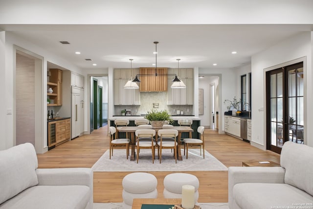 dining space featuring wine cooler, recessed lighting, light wood-type flooring, bar, and baseboards