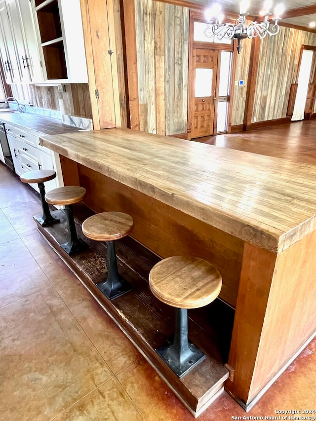 bar with white cabinetry, butcher block countertops, sink, and tile floors