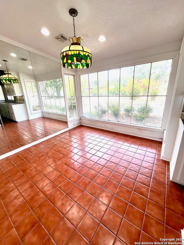 unfurnished dining area featuring tile flooring and a textured ceiling