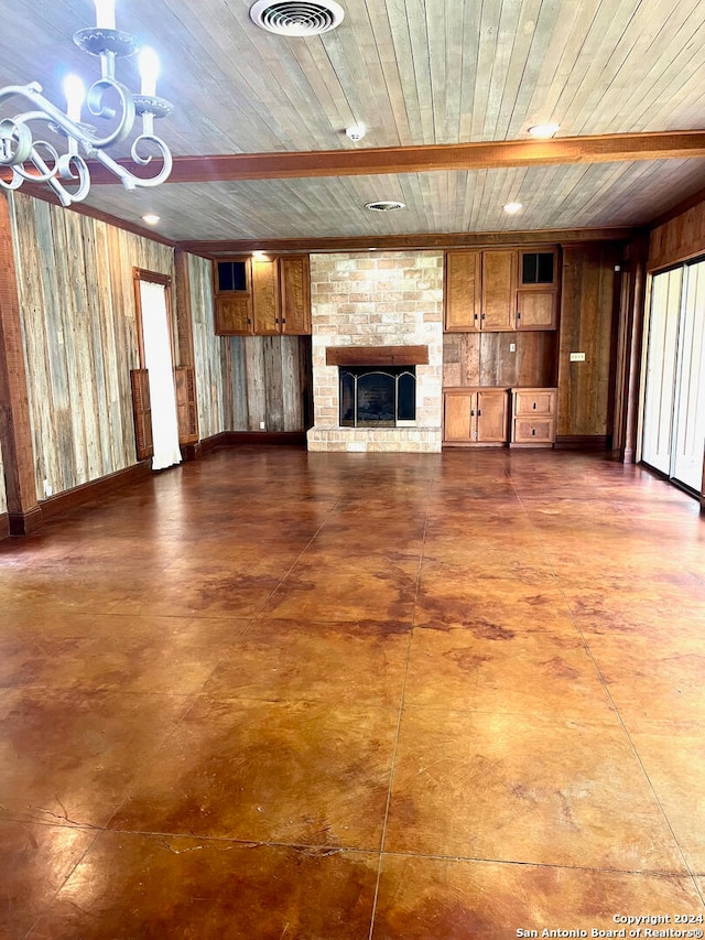 unfurnished living room with a notable chandelier, plenty of natural light, wood ceiling, and a brick fireplace