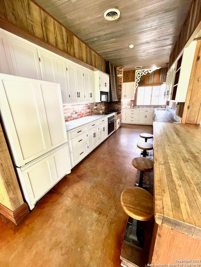 kitchen with white cabinets, wood ceiling, and wood walls