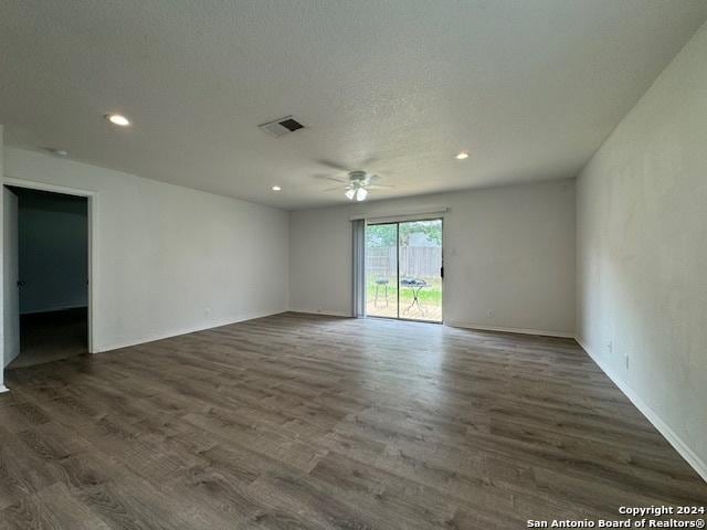 empty room with ceiling fan, dark hardwood / wood-style flooring, and a textured ceiling