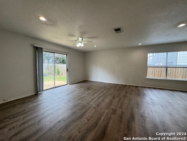 empty room with ceiling fan, dark hardwood / wood-style flooring, and a textured ceiling