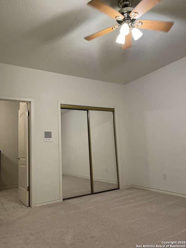 unfurnished bedroom with light carpet, ceiling fan, and a closet