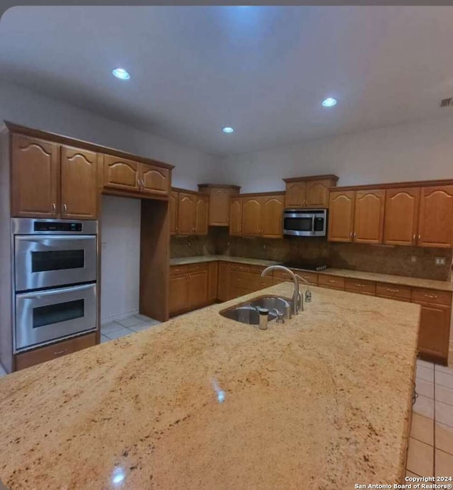 kitchen featuring sink, appliances with stainless steel finishes, backsplash, and light tile patterned floors