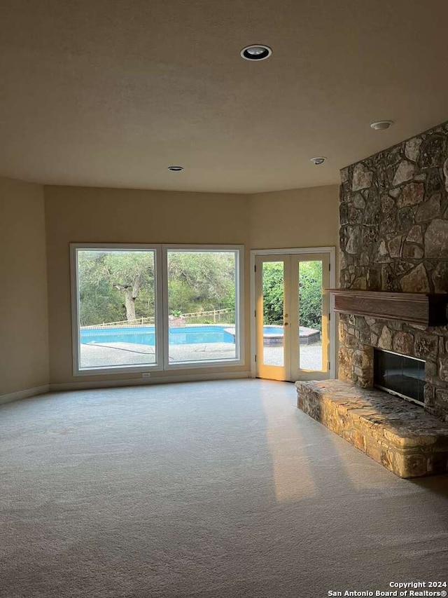 unfurnished living room with carpet flooring, a fireplace, and french doors