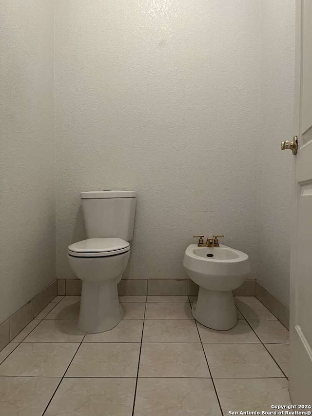 bathroom with a bidet, toilet, and tile patterned floors