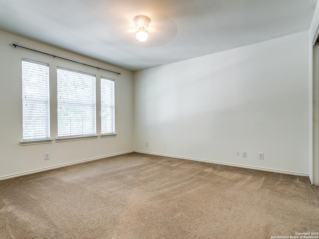 empty room with carpet flooring, ceiling fan, and plenty of natural light