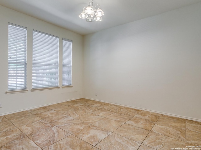 spare room with a chandelier and light tile patterned floors