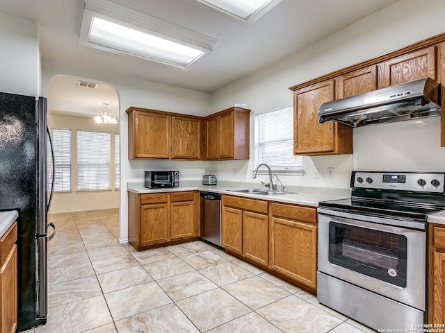 kitchen with sink, plenty of natural light, a chandelier, exhaust hood, and appliances with stainless steel finishes