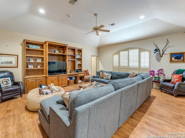 living room with a tray ceiling, light hardwood / wood-style flooring, ceiling fan, and lofted ceiling