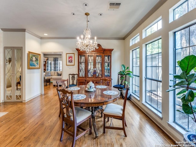 dining area with light wood-type flooring, crown molding, and a chandelier