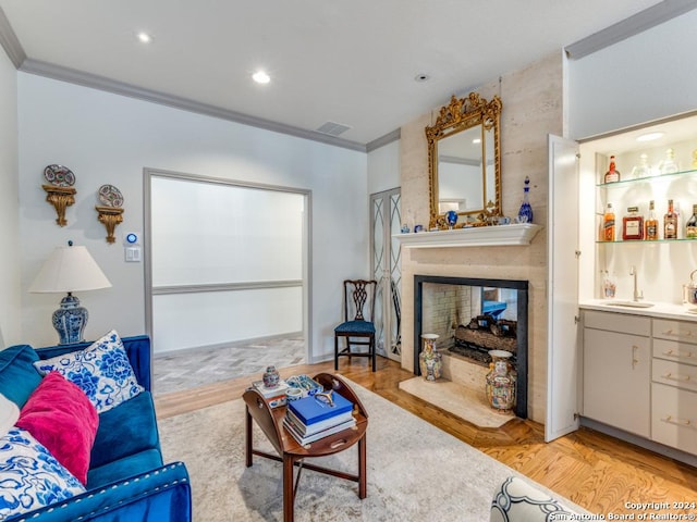 living room with a multi sided fireplace, light hardwood / wood-style floors, crown molding, and indoor wet bar