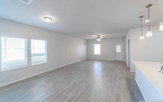 unfurnished living room featuring ceiling fan, wood finished floors, and baseboards