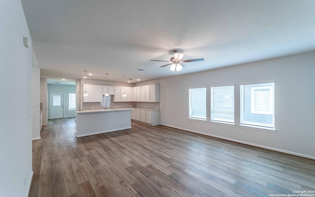 kitchen with light hardwood / wood-style floors, pendant lighting, white cabinets, and a center island