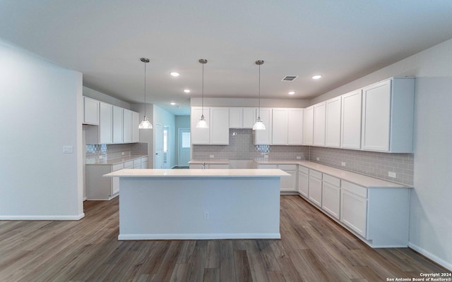 kitchen with dark hardwood / wood-style floors, a kitchen island, pendant lighting, and white cabinets