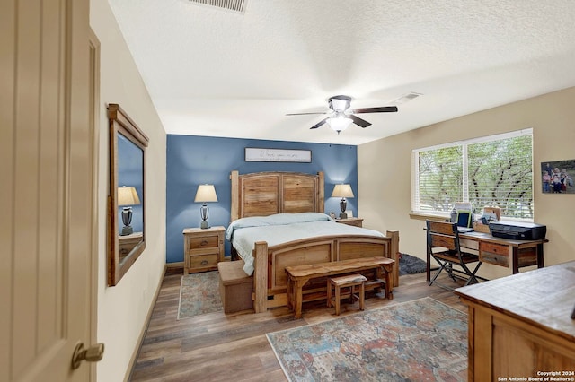 bedroom with hardwood / wood-style flooring, ceiling fan, and a textured ceiling