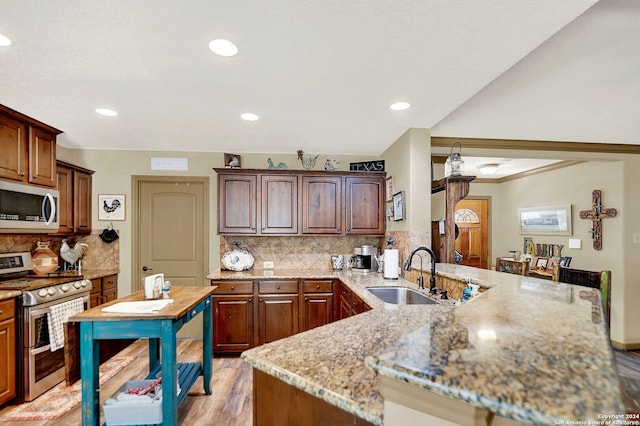 kitchen featuring stainless steel appliances, sink, tasteful backsplash, and kitchen peninsula