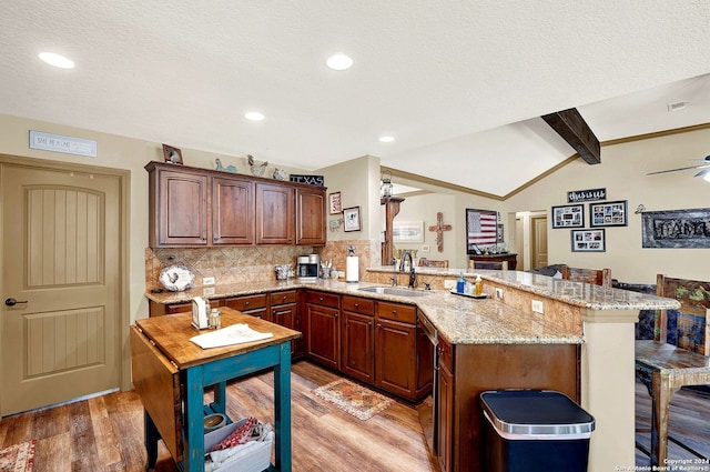 kitchen with light hardwood / wood-style flooring, kitchen peninsula, ceiling fan, sink, and lofted ceiling with beams