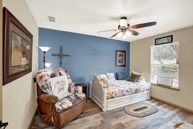 bedroom featuring ceiling fan, a textured ceiling, and hardwood / wood-style flooring