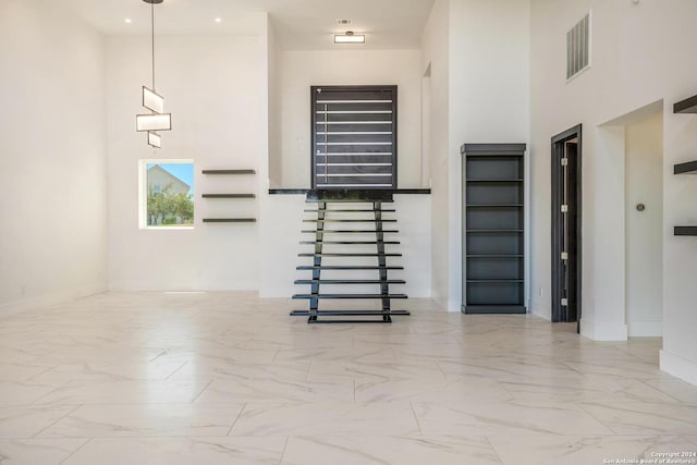 unfurnished living room featuring tile floors and a towering ceiling