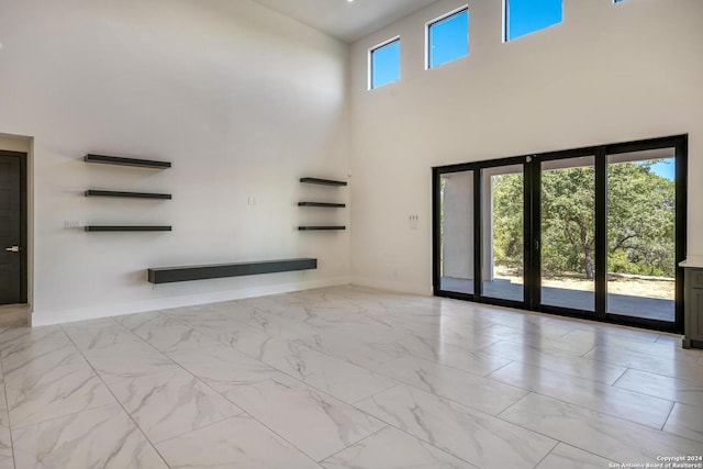 spare room featuring a towering ceiling and light tile flooring