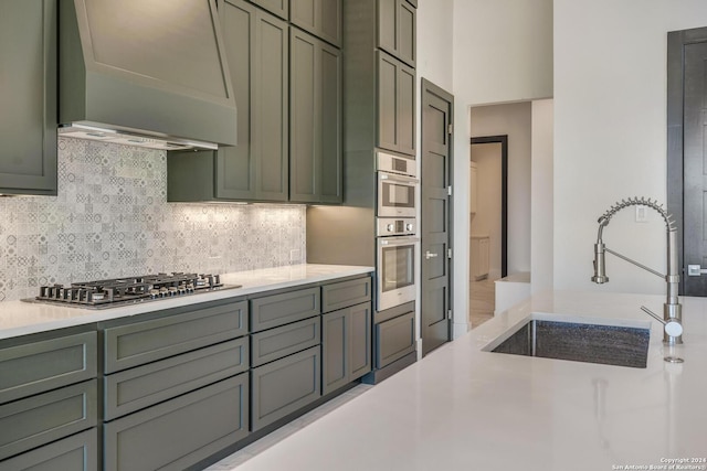 kitchen featuring light hardwood / wood-style floors, custom exhaust hood, stainless steel appliances, backsplash, and sink