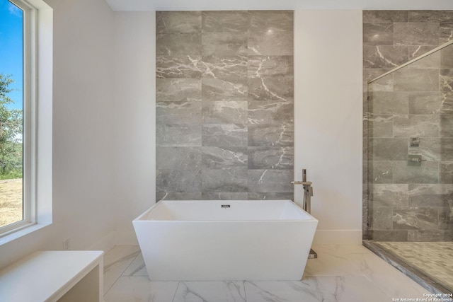 bathroom with tile floors, a washtub, and tile walls