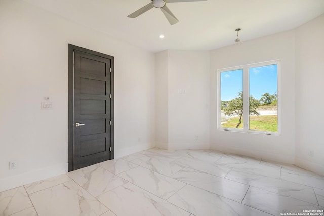 tiled spare room featuring ceiling fan