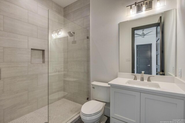 bathroom with tiled shower, ceiling fan, toilet, and large vanity