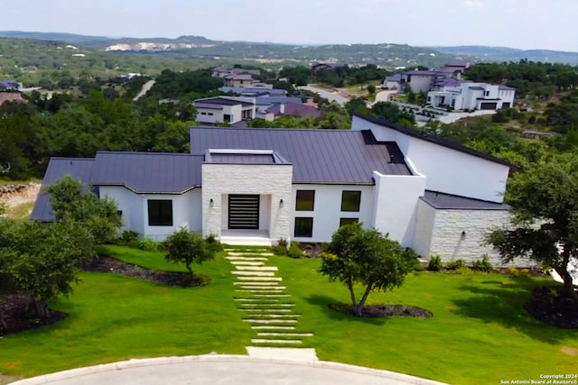 view of front of property featuring stucco siding, a front yard, a standing seam roof, metal roof, and stone siding