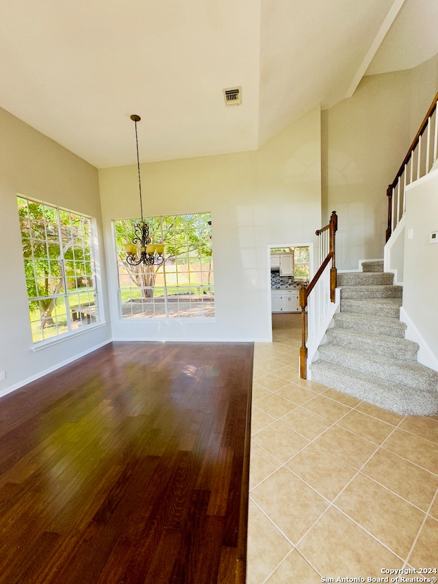 interior space featuring a healthy amount of sunlight, high vaulted ceiling, a chandelier, and tile floors