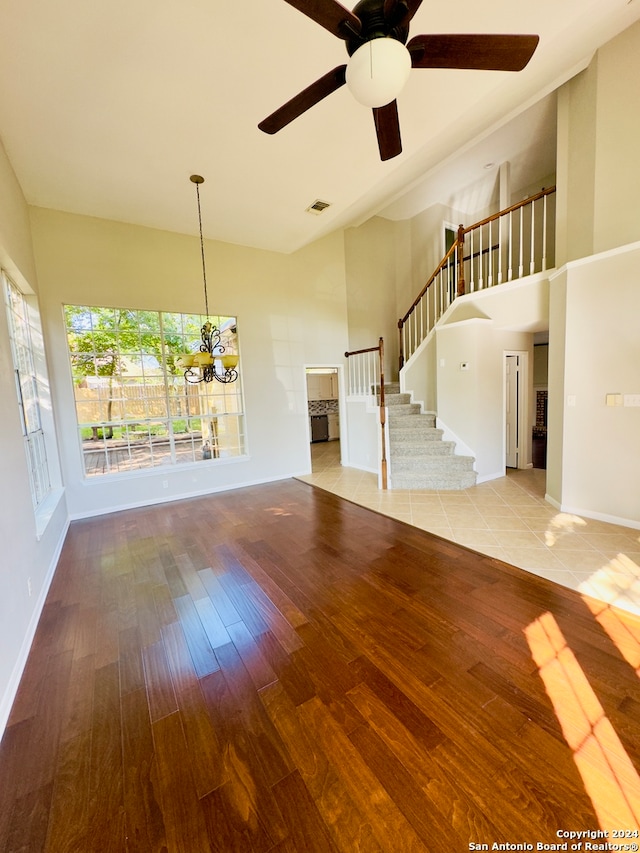 unfurnished living room featuring light wood-type flooring and ceiling fan with notable chandelier