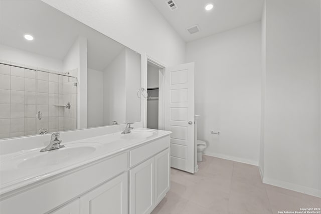 bathroom featuring tile patterned flooring, vanity, a shower with shower door, and toilet