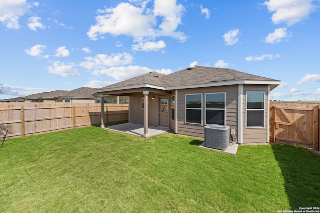 rear view of property with a yard, cooling unit, and a patio area